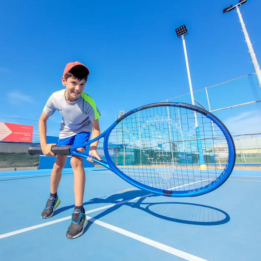 young boy with giant tennis racquet